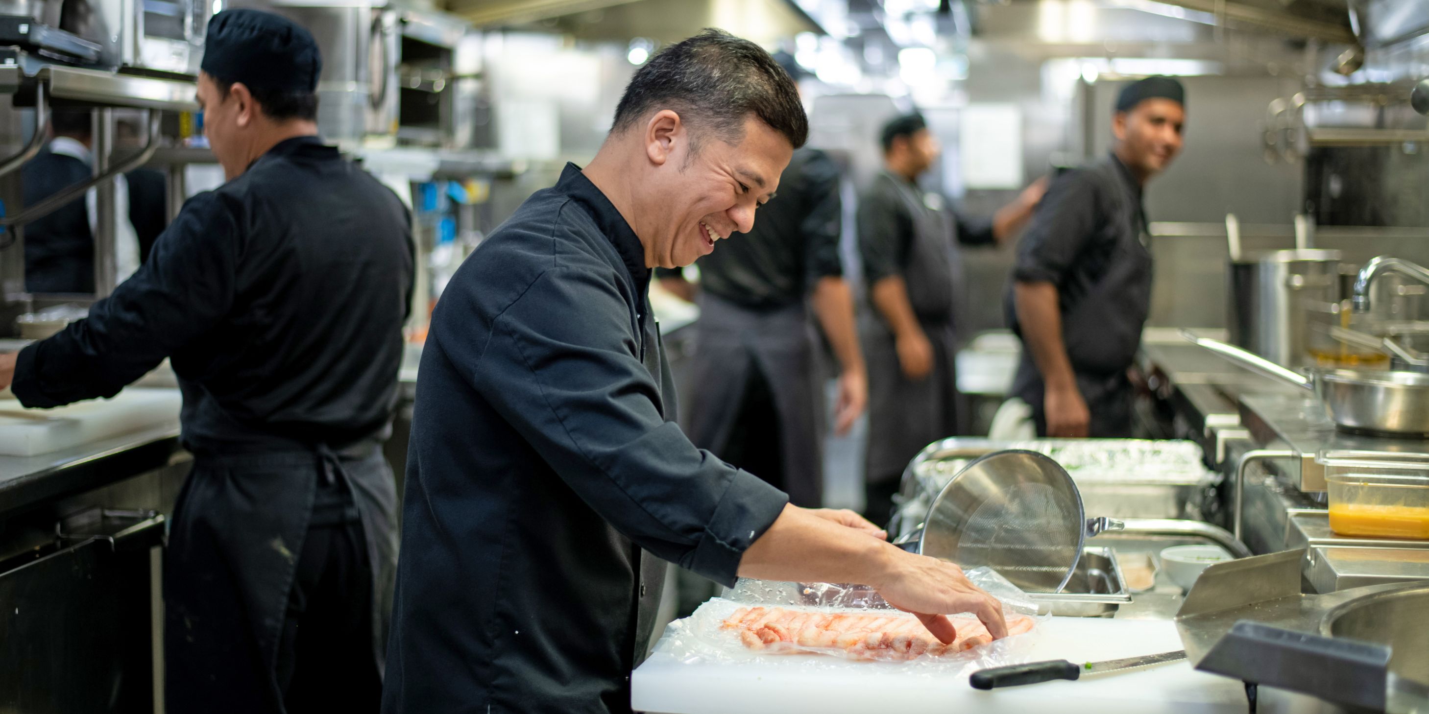 Kitchen hand assisting with prep in a kitchen onboard a luxury ocean cruise vessel