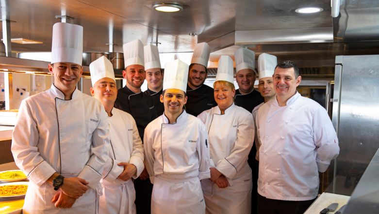 Group of the Kitchen Crew posing for a photo in their uniforms